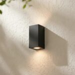 Aplique de pared MONACO difusor bi-direccional negro moderno de hierro para interior, iluminando una pared texturizada.