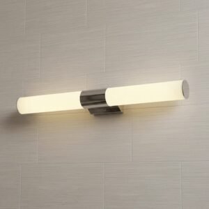 Aplique de pared LED moderno cromado con luz cálida sobre fondo de baldosas claras, ideal para baño o dormitorio.