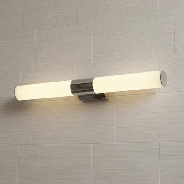 Aplique de pared LED moderno cromado con luz cálida sobre fondo de baldosas claras, ideal para baño o dormitorio.