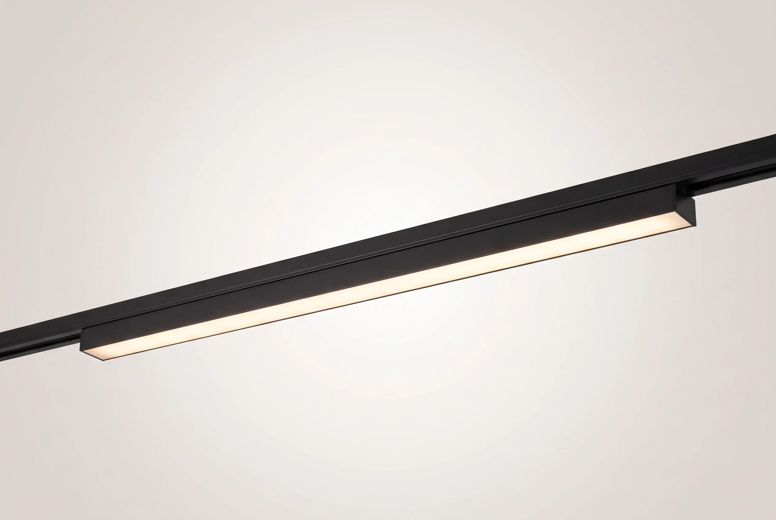 Difusor lineal Smart de 20W montado en un tramo de riel magnético negro sobre fondo claro, proyectando una línea de luz continua y cálida